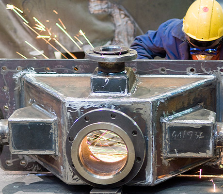 Employee performing welding on spare part for plant