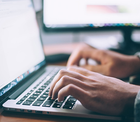 Hands typing on a laptop